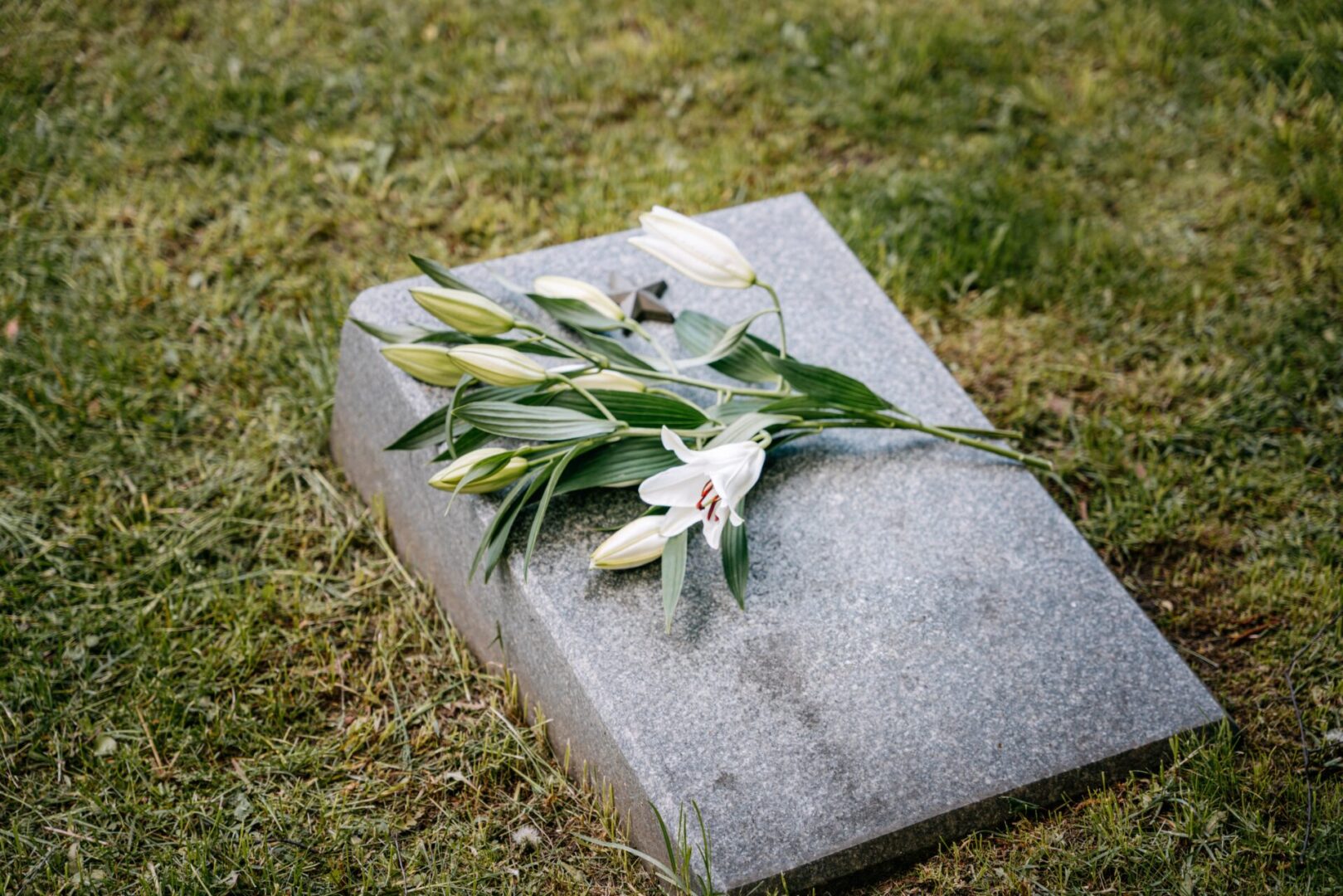 A grave with flowers on it laying in the grass.